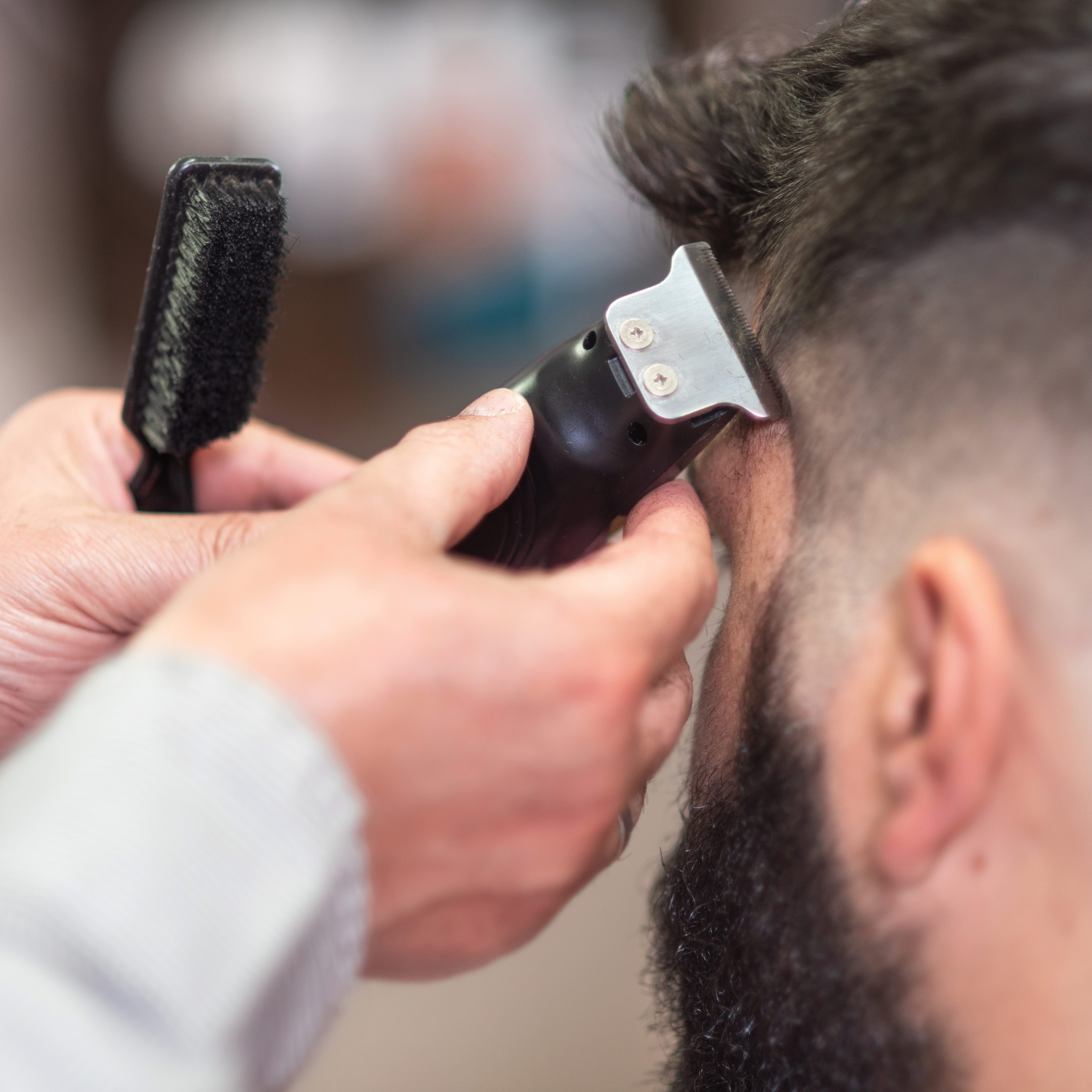 Cropped Hands Of Barber Cutting Male Customer Hair In Salon