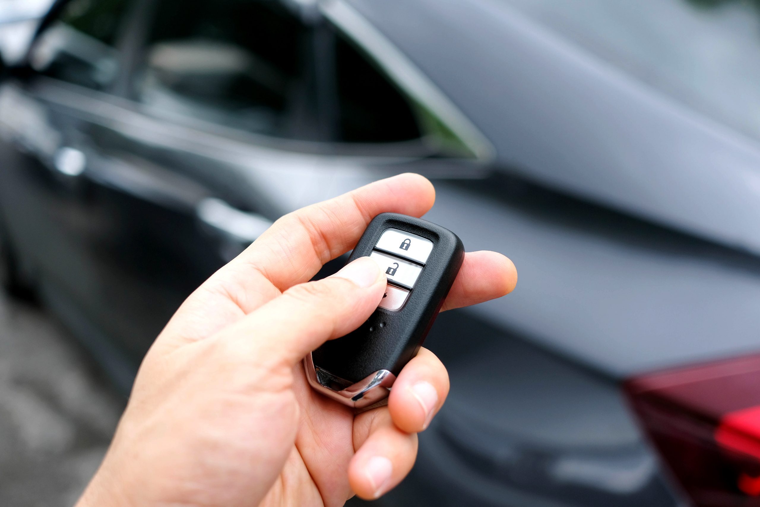 Man hand holding the car remote, he push the remote control to open the car door