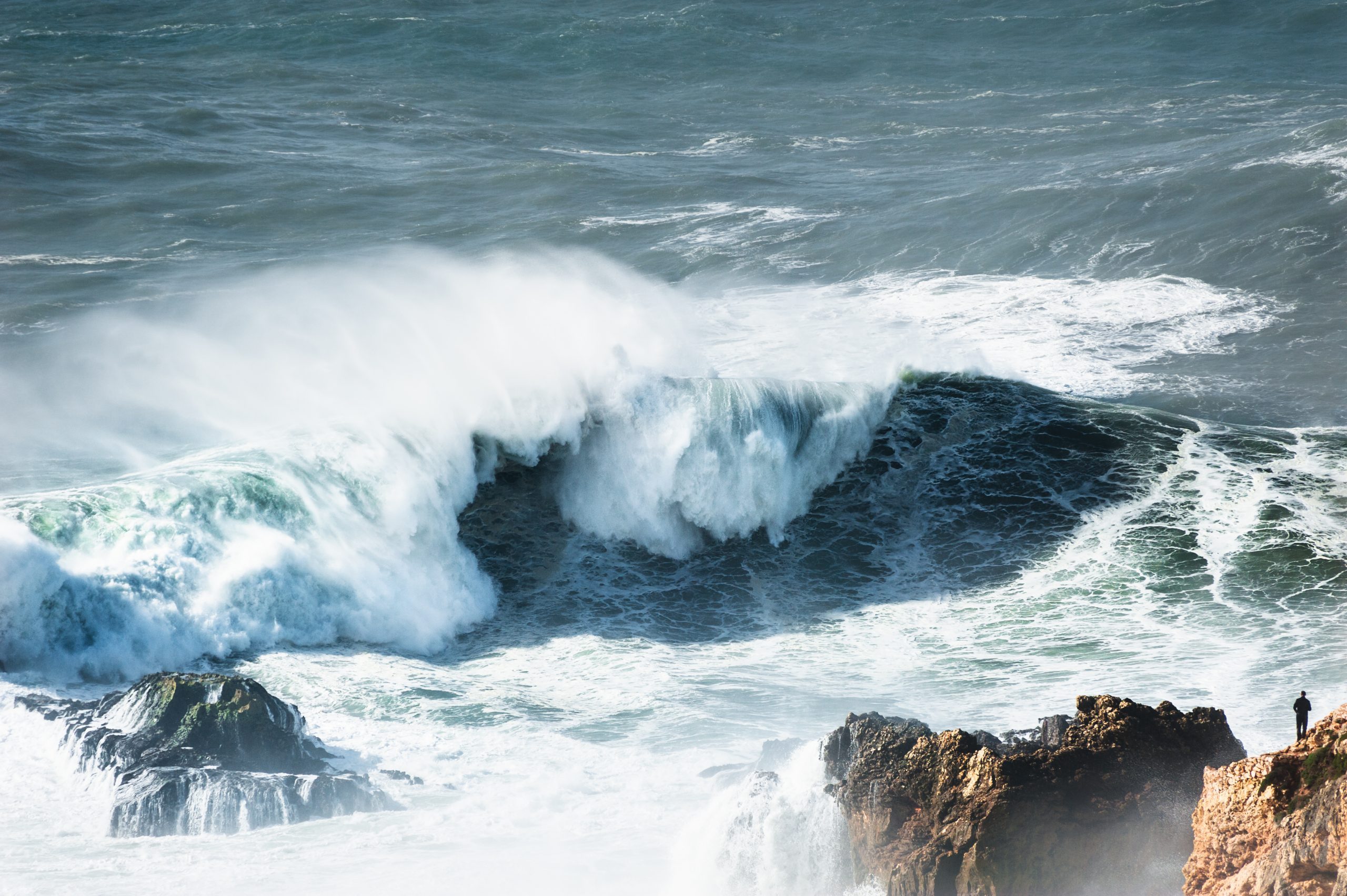 Man watching big waves in Nazare, Portugal.