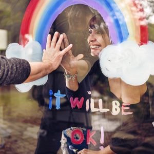 Woman painting a rainbow on a window