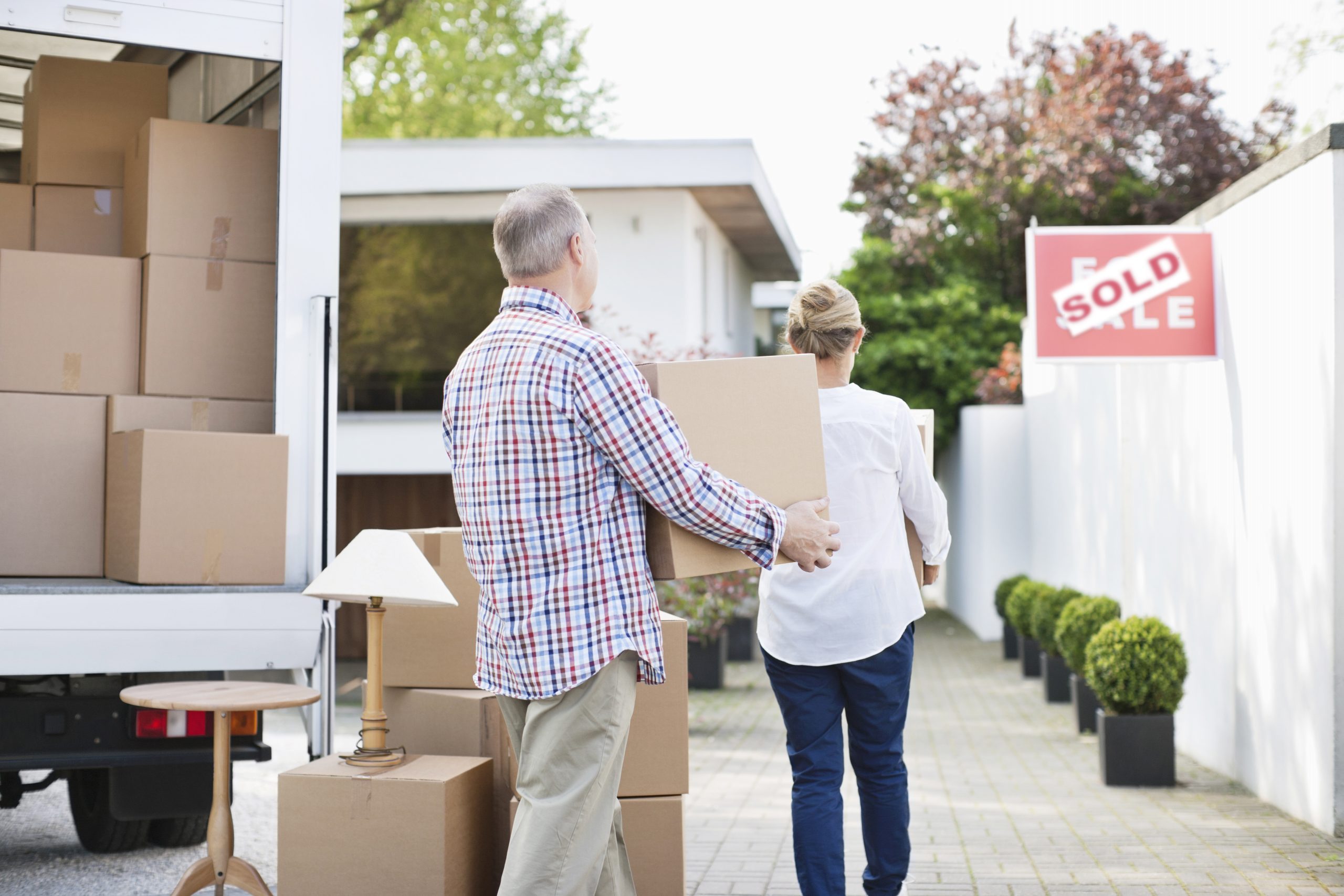 Couple unloading boxes from moving van