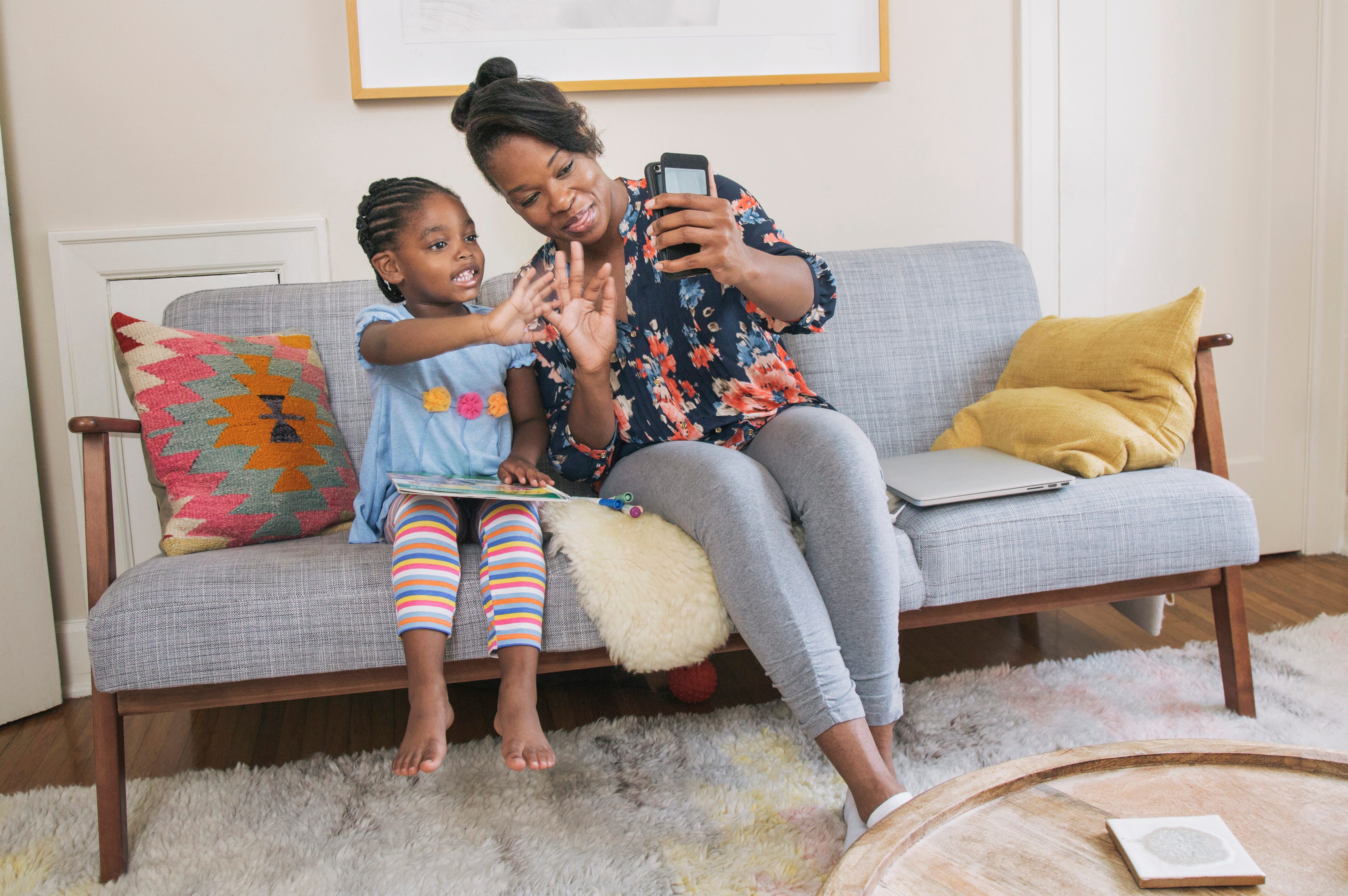 African American mother and daughter taking selfie in living room