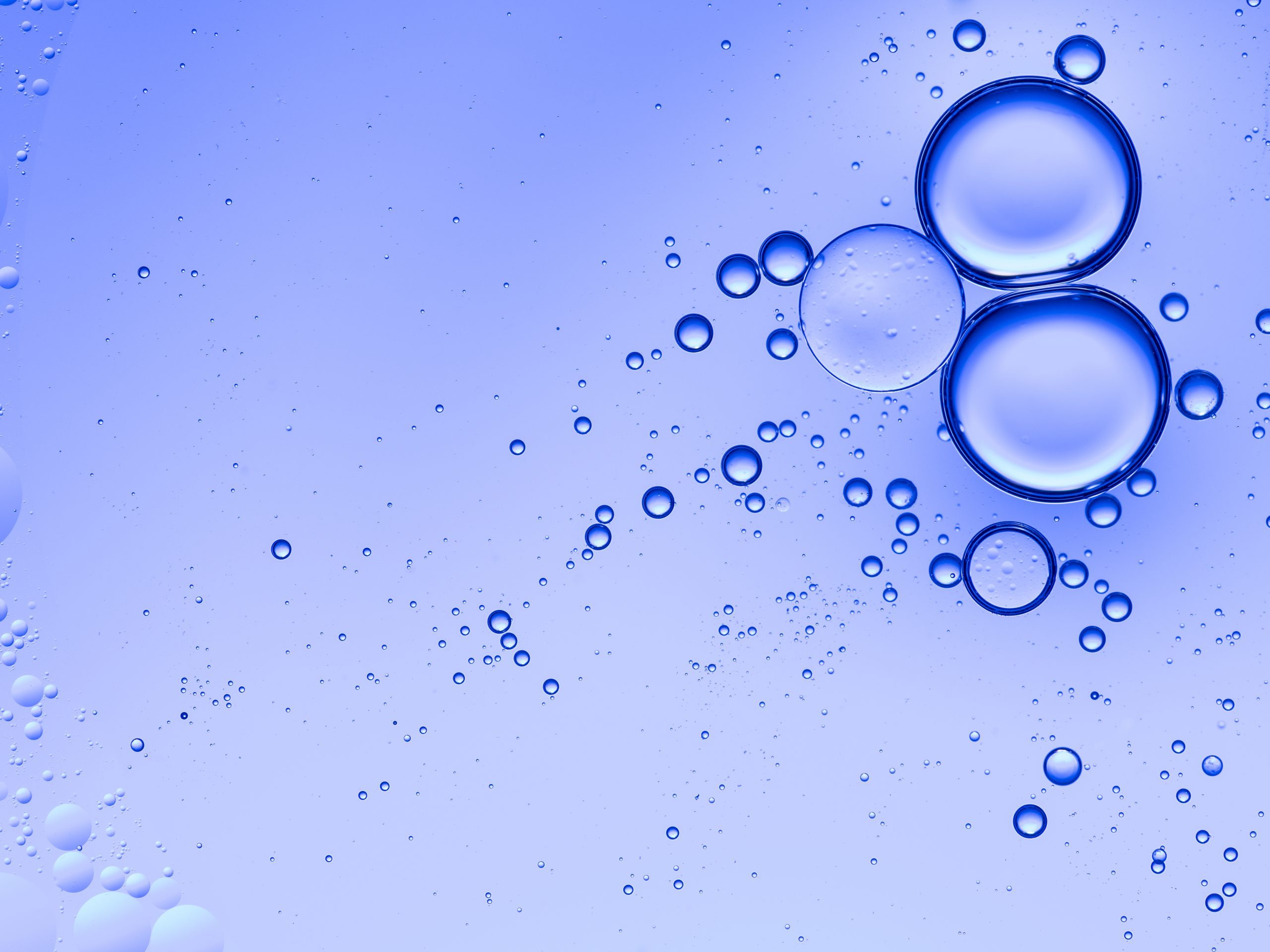 Oil drops and bubbles floating over water with a blue background