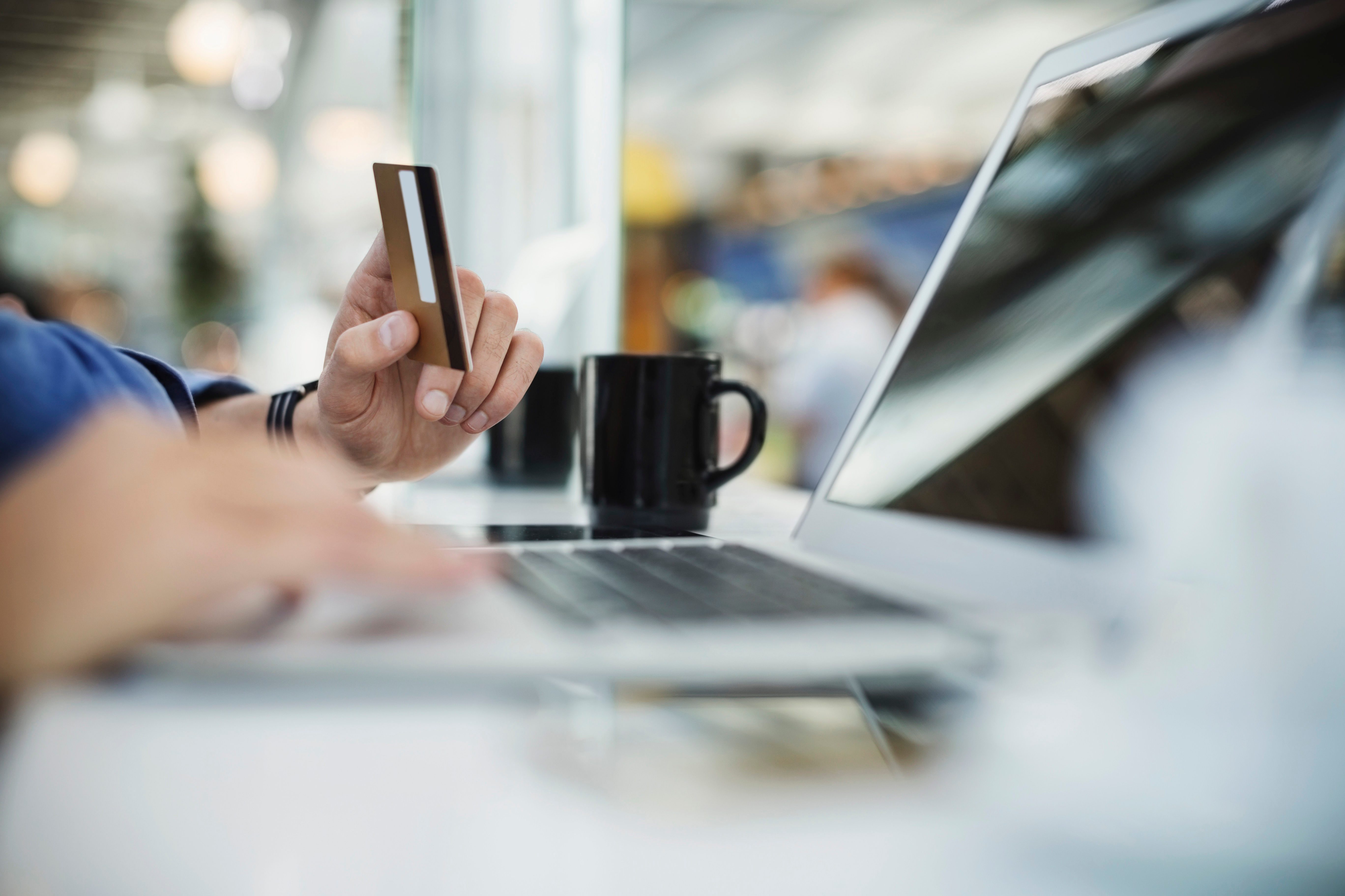 Cropped image of businessman using credit card and laptop at airport lobby