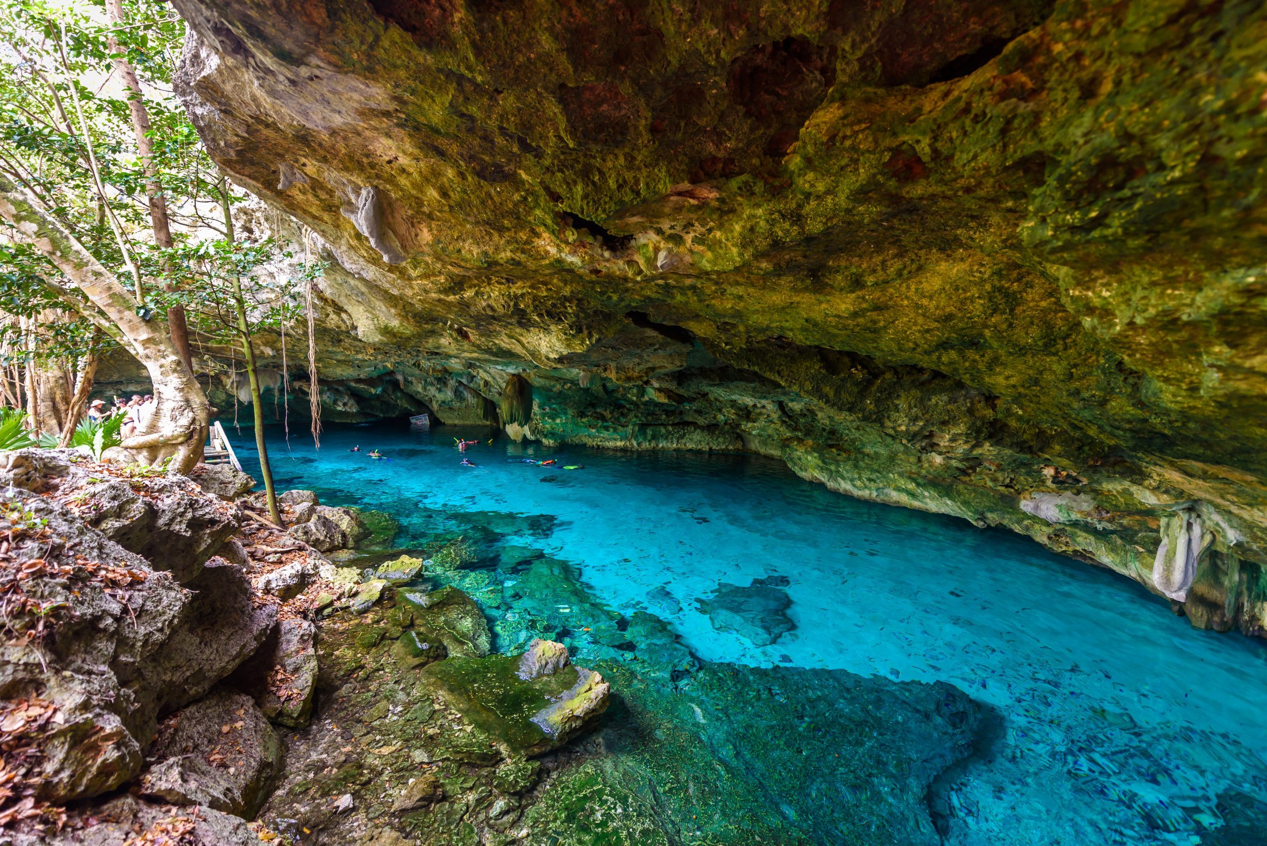 Cenote Dos Ojos in Quintana Roo, Mexico. People swimming and snorkeling in clear blue water. This cenote is located close to Tulum in Yucatan peninsula, Mexico.