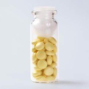 glass pill bottle with pills and a cotton ball inside