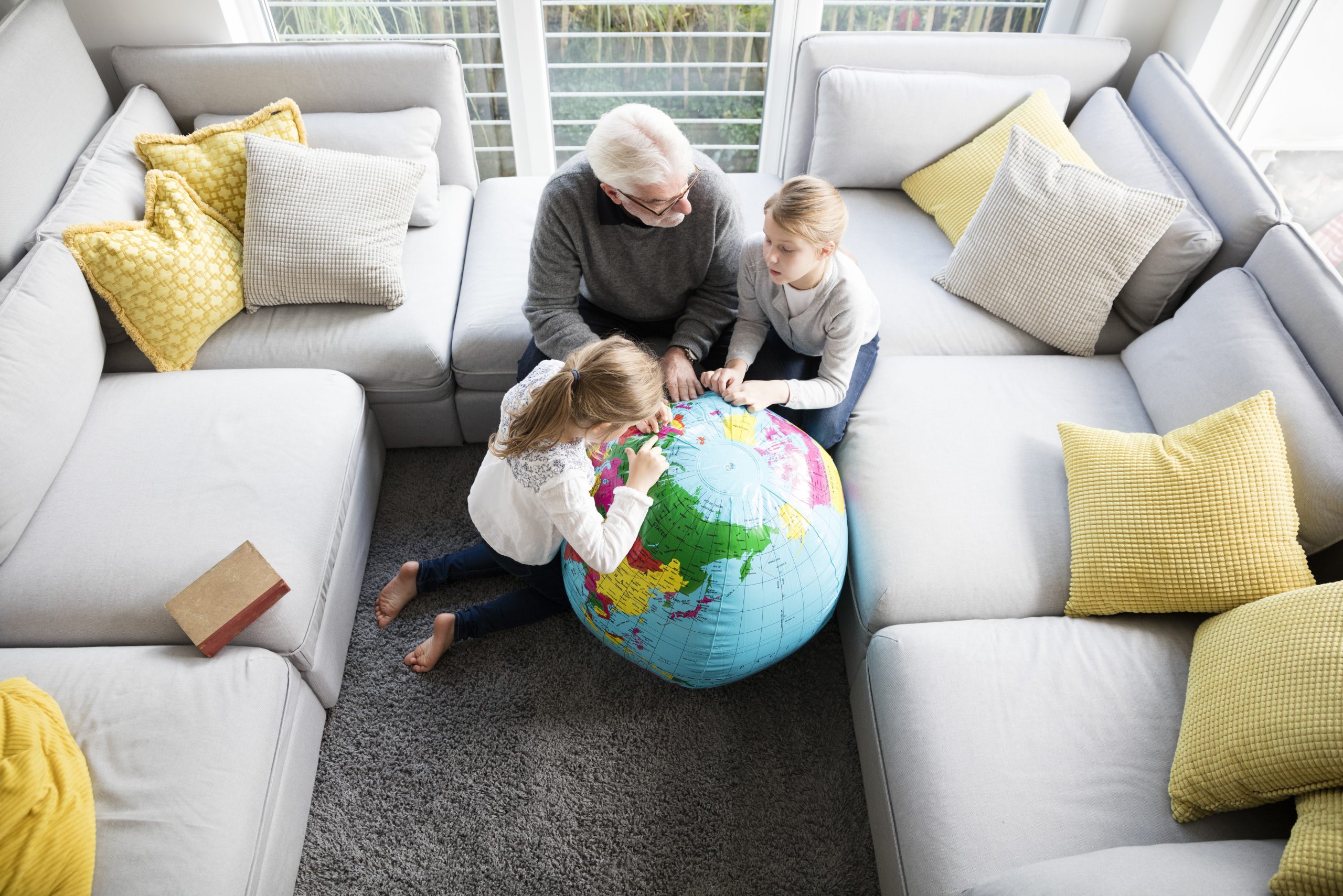 Two girls and grandfather with globe in living room