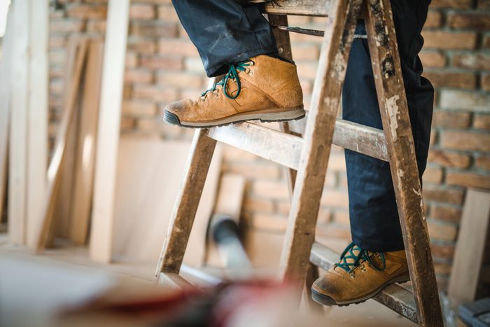 Unrecognizable manual worker moving up the ladders at construction site.
