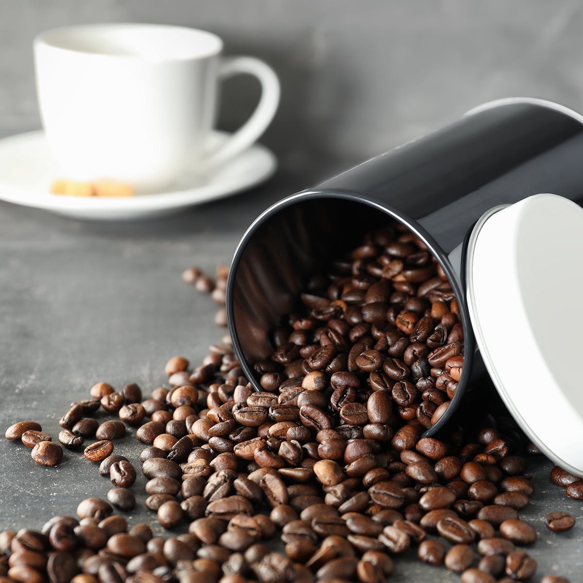 Overturned container with roasted coffee beans on table