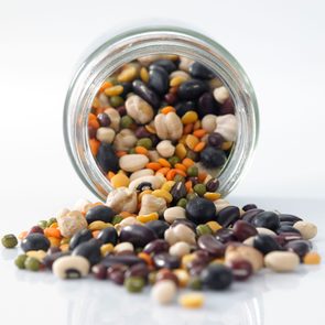 Close-Up Of Lentils and Beans Spilling From a glass Jar On White Background