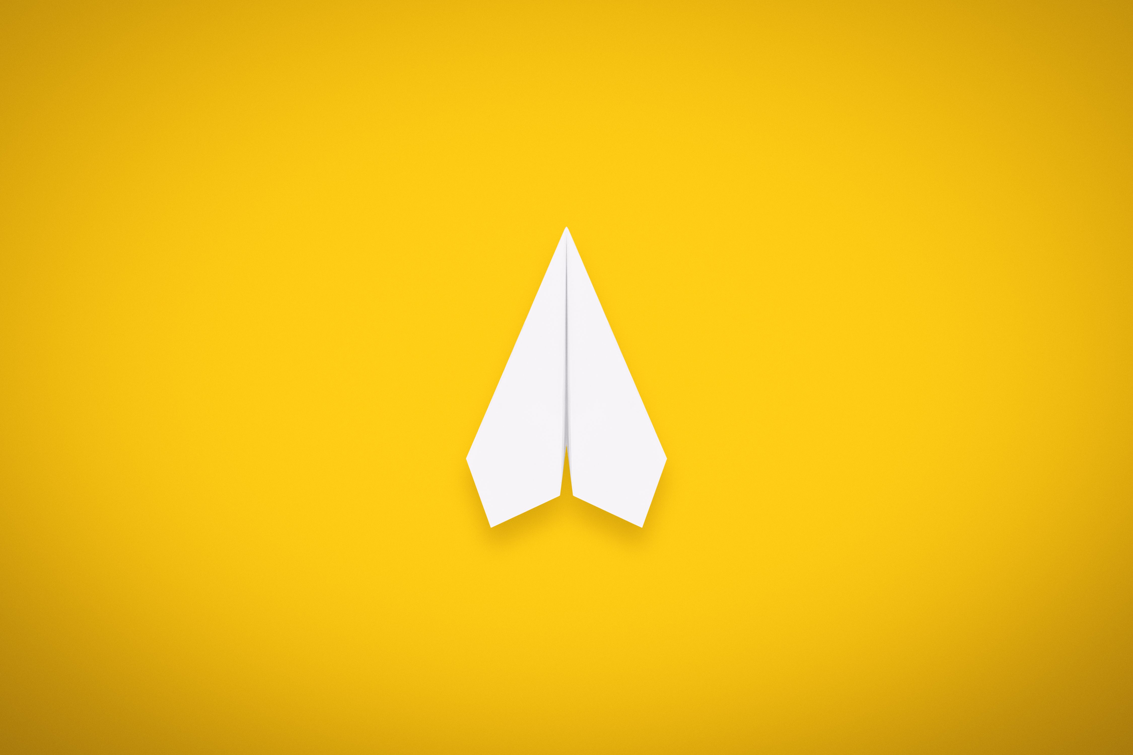A Single Paper Airplane on Yellow Background