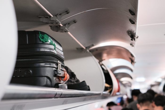 overhead locker on airplane,Passenger put cabin bag cabin on the top shelf. Travel concept