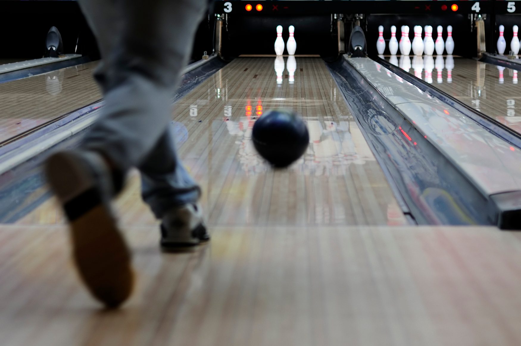 Person Throwing a Bowling Ball Down the Alley Lanes