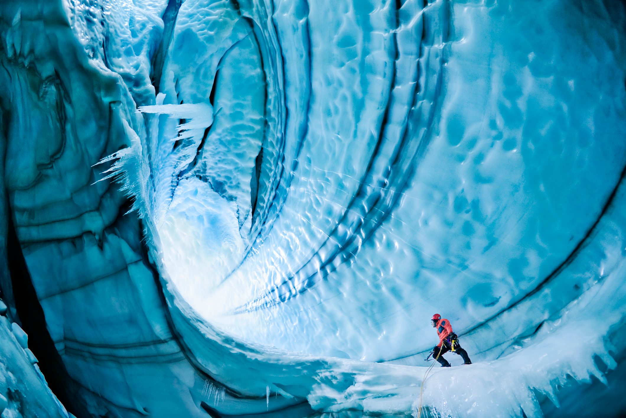 Male ice climber exploring ice cave, low angle view