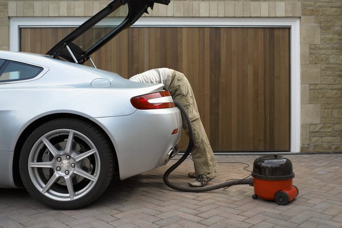 Young man leaning into boot of car, side view