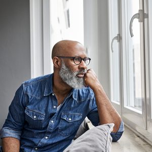 Mature man sitting at window, looking worried