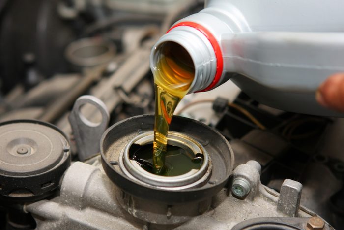 In auto repair shop...Car mechanic is changing engine oil