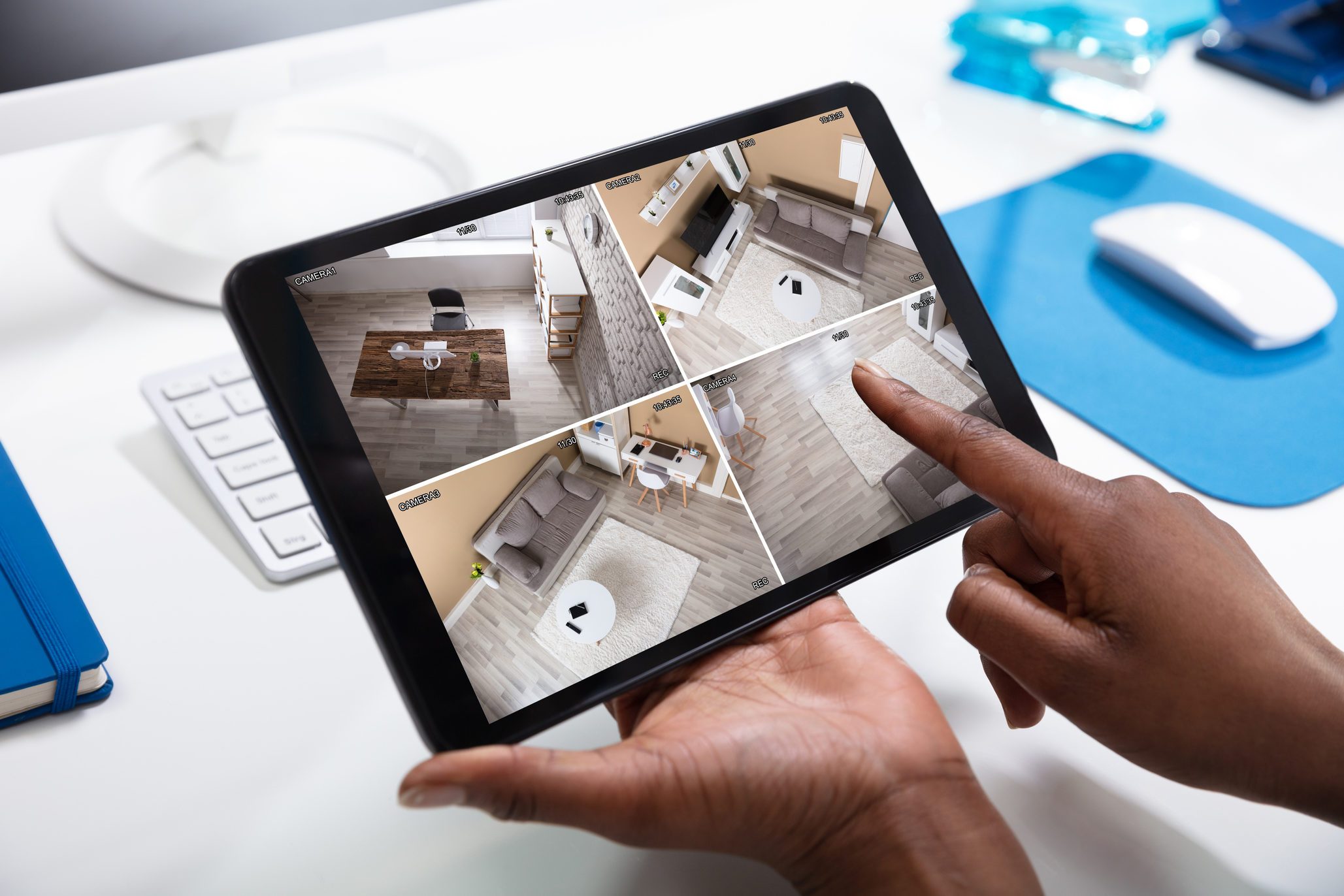 Person's Hand Monitoring CCTV Footage On Tablet