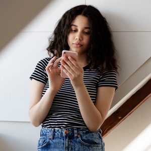 Teenage girl texting in room