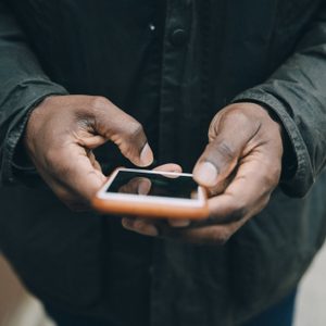 Midsection of businessman using smart phone while standing on footbridge in city