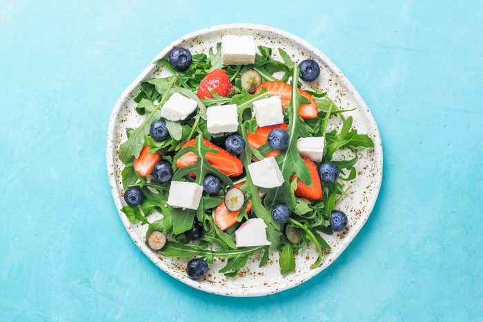 overhead view of a festive 4th of july red, white, and blue salad with strawberries, blueberries, and feta