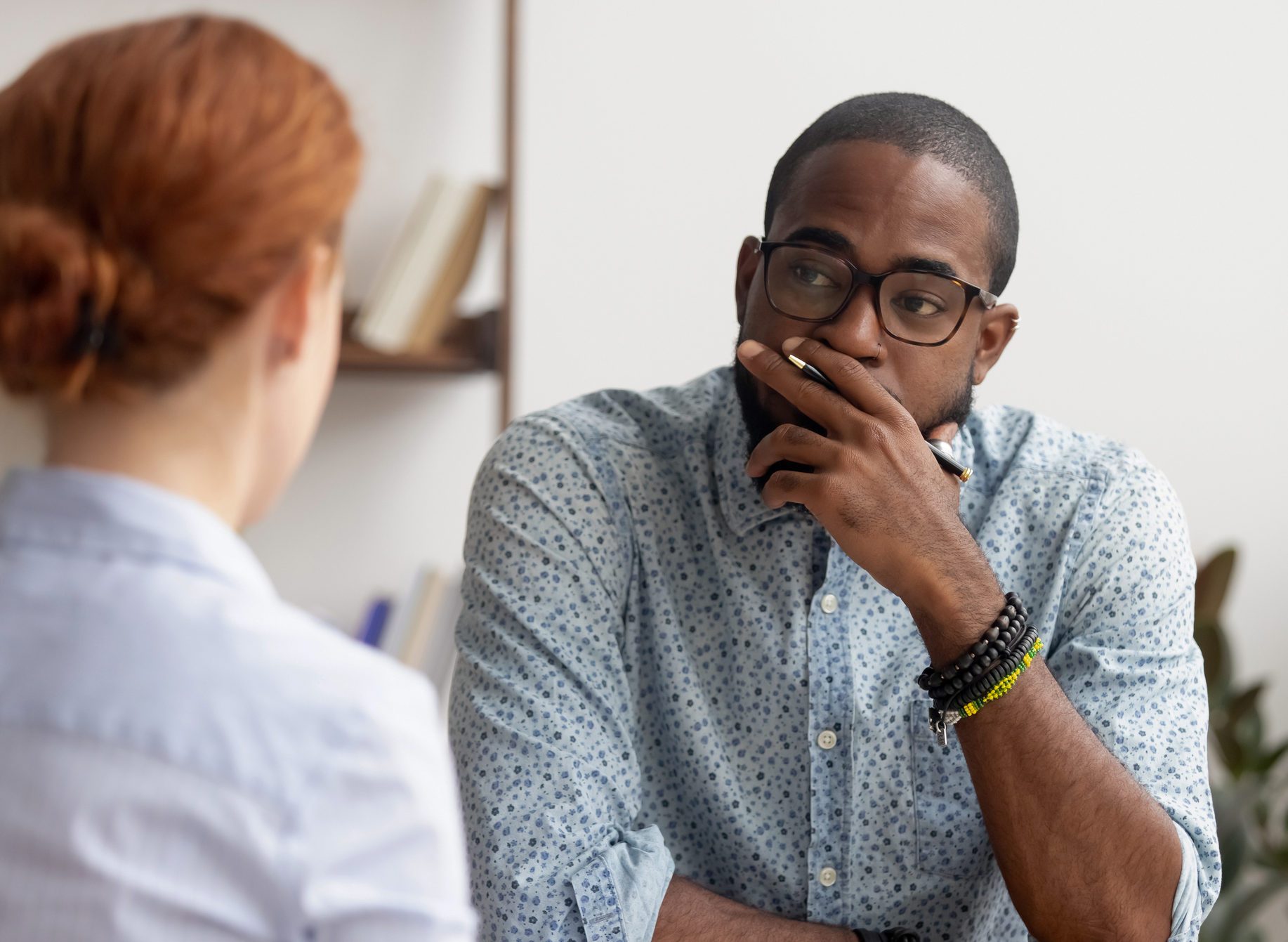 Doubtful african hr talking to caucasian applicant at job interview