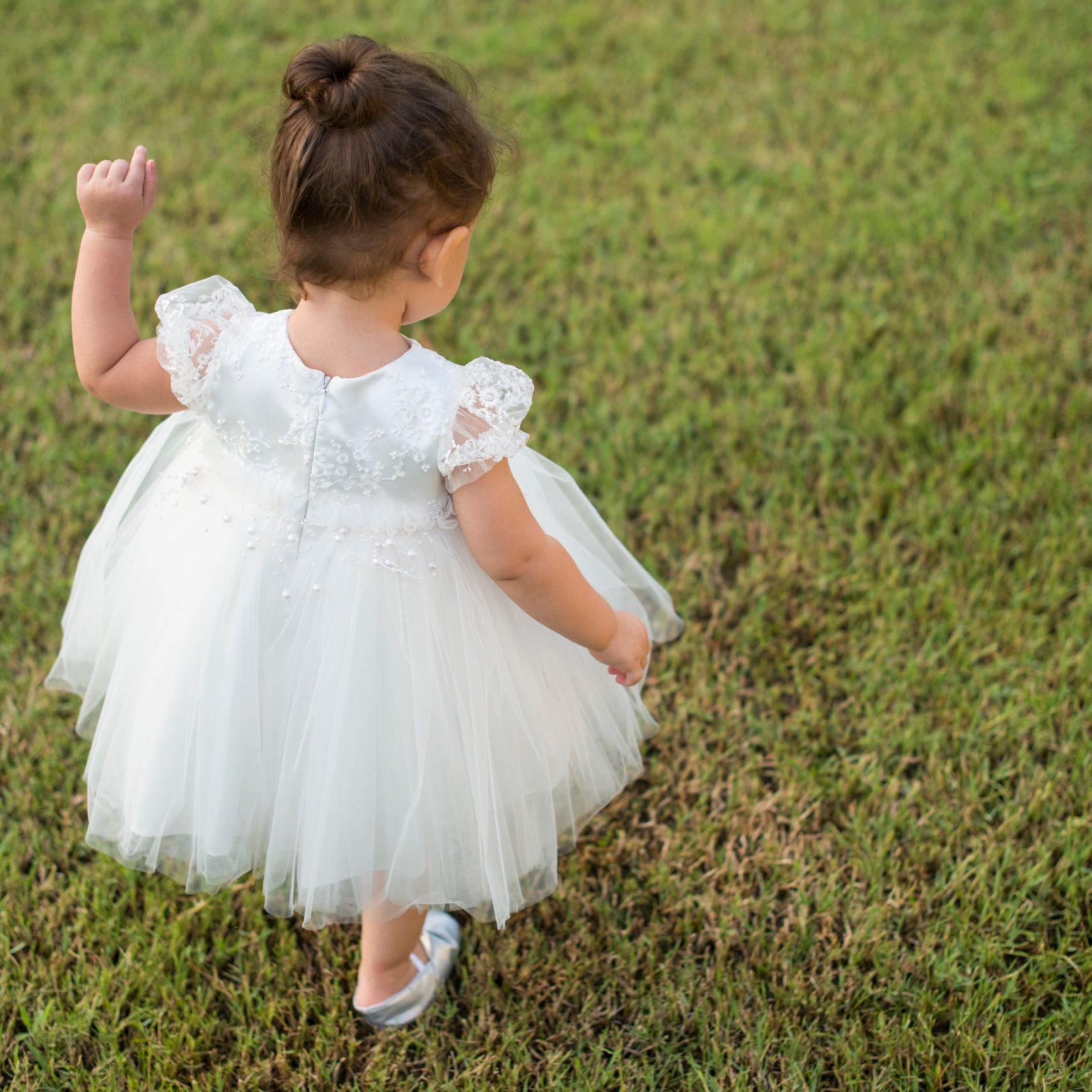 Toddler girl in a white dress on lawn