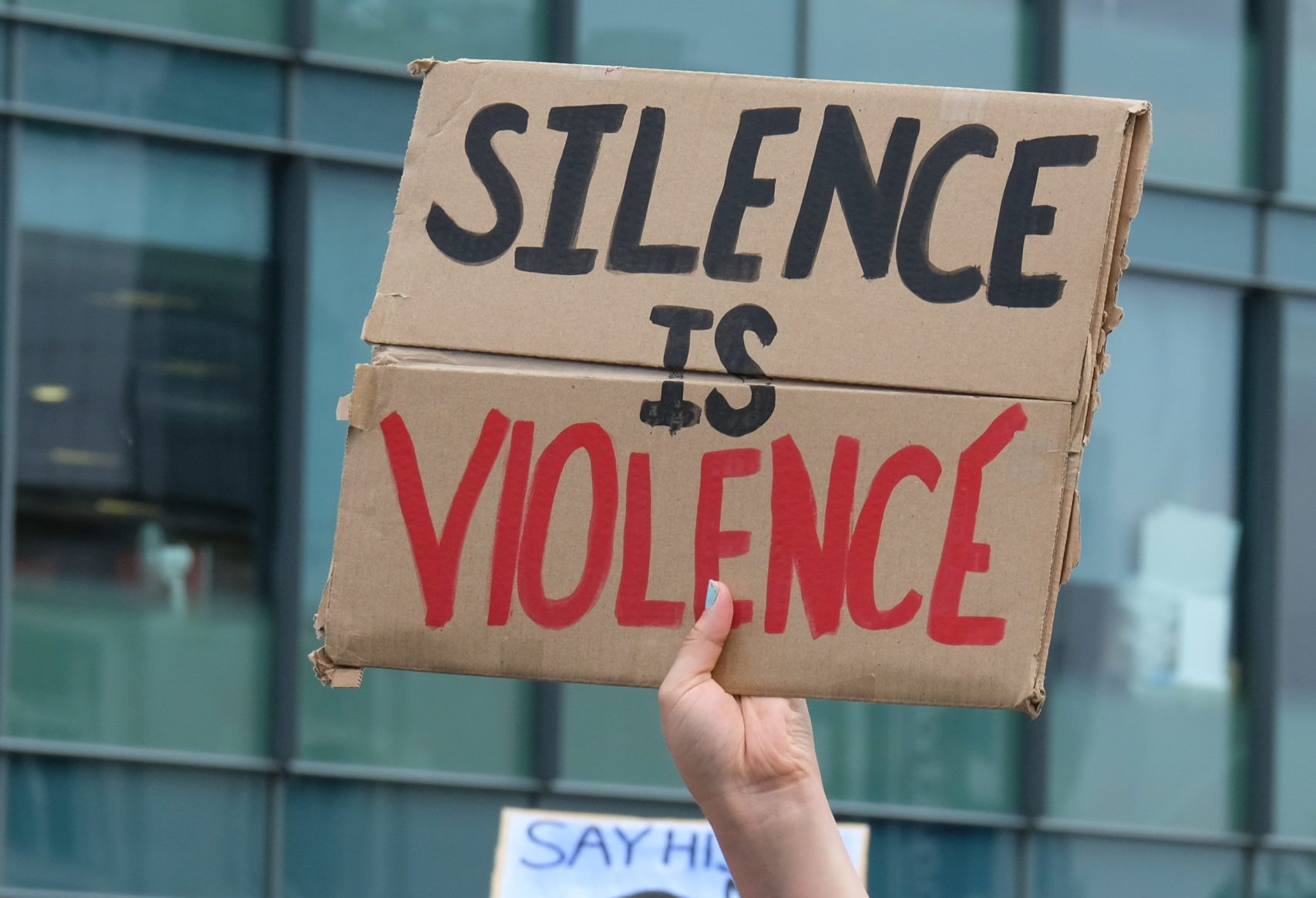 A protester wearing a face mask holds a placard that says...