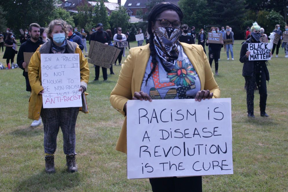 Protesters wearing face masks hold placards during the...