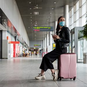 Young woman at the airport with luggage, wearing N95 face masks