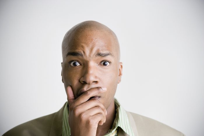 African businessman with hand covering mouth and chin
