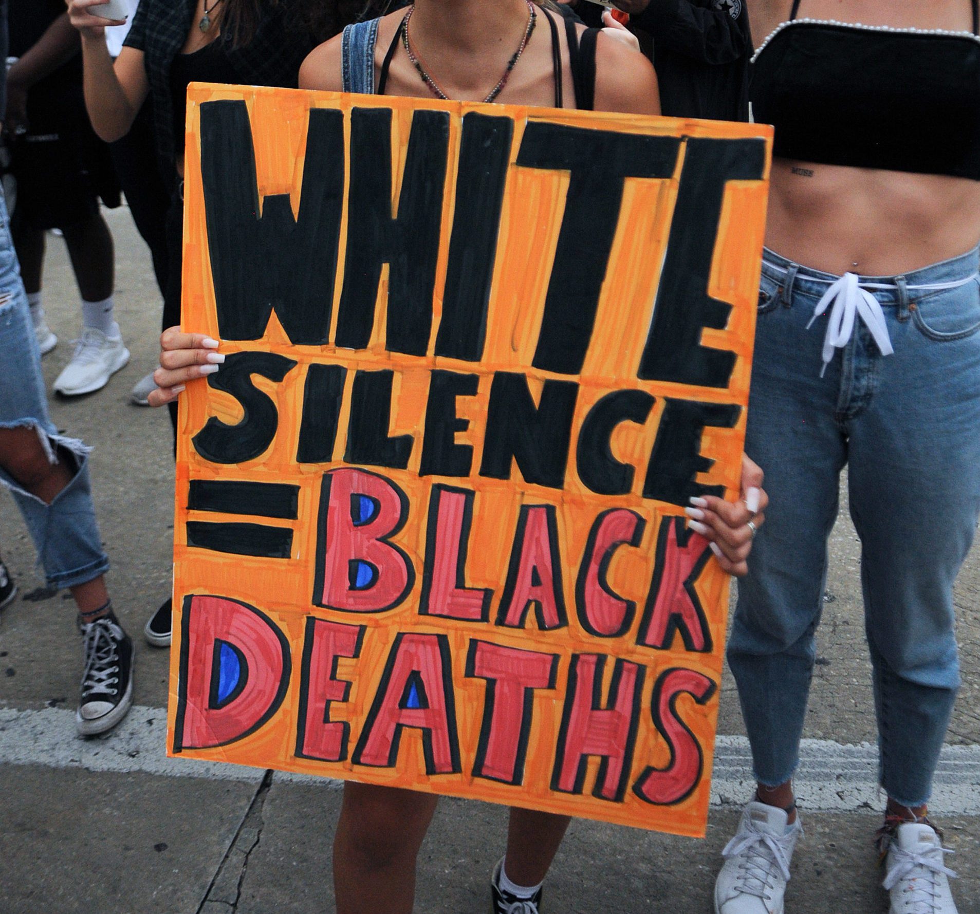 A protester chants slogans while holding a placard saying '...