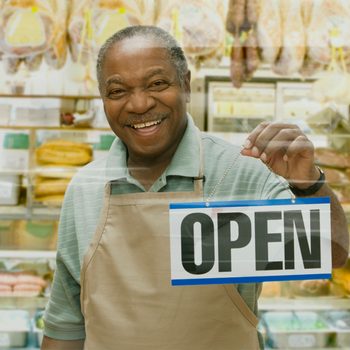 African butcher holding ""Open"" sign