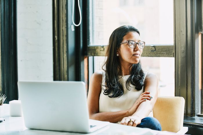 Businesswoman looking out window while seated at desk in office