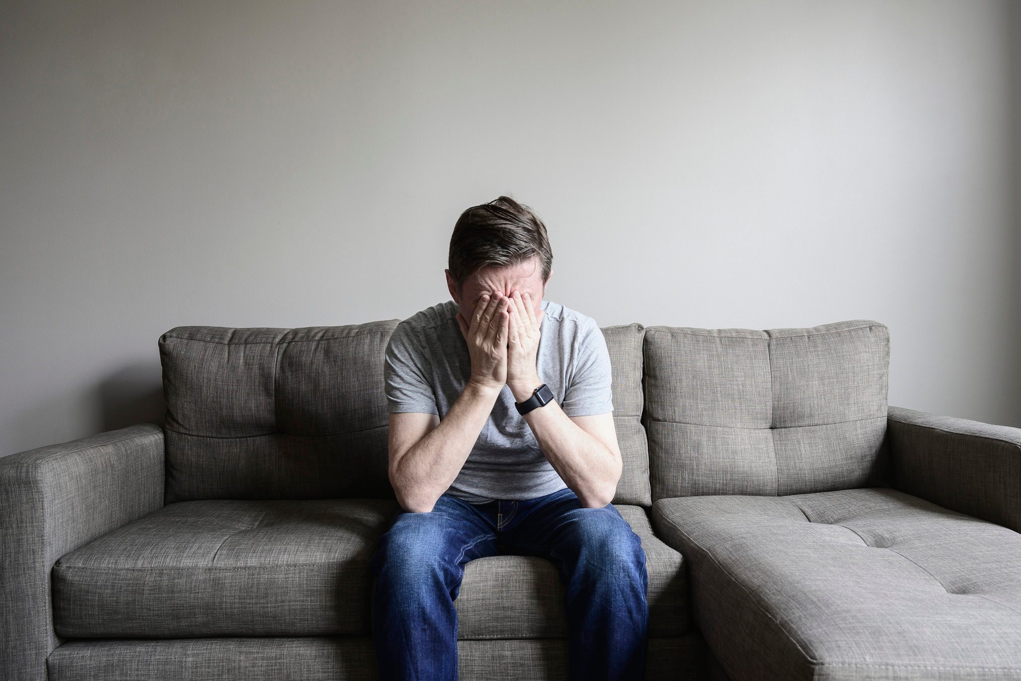 Depressed mature man sitting on couch