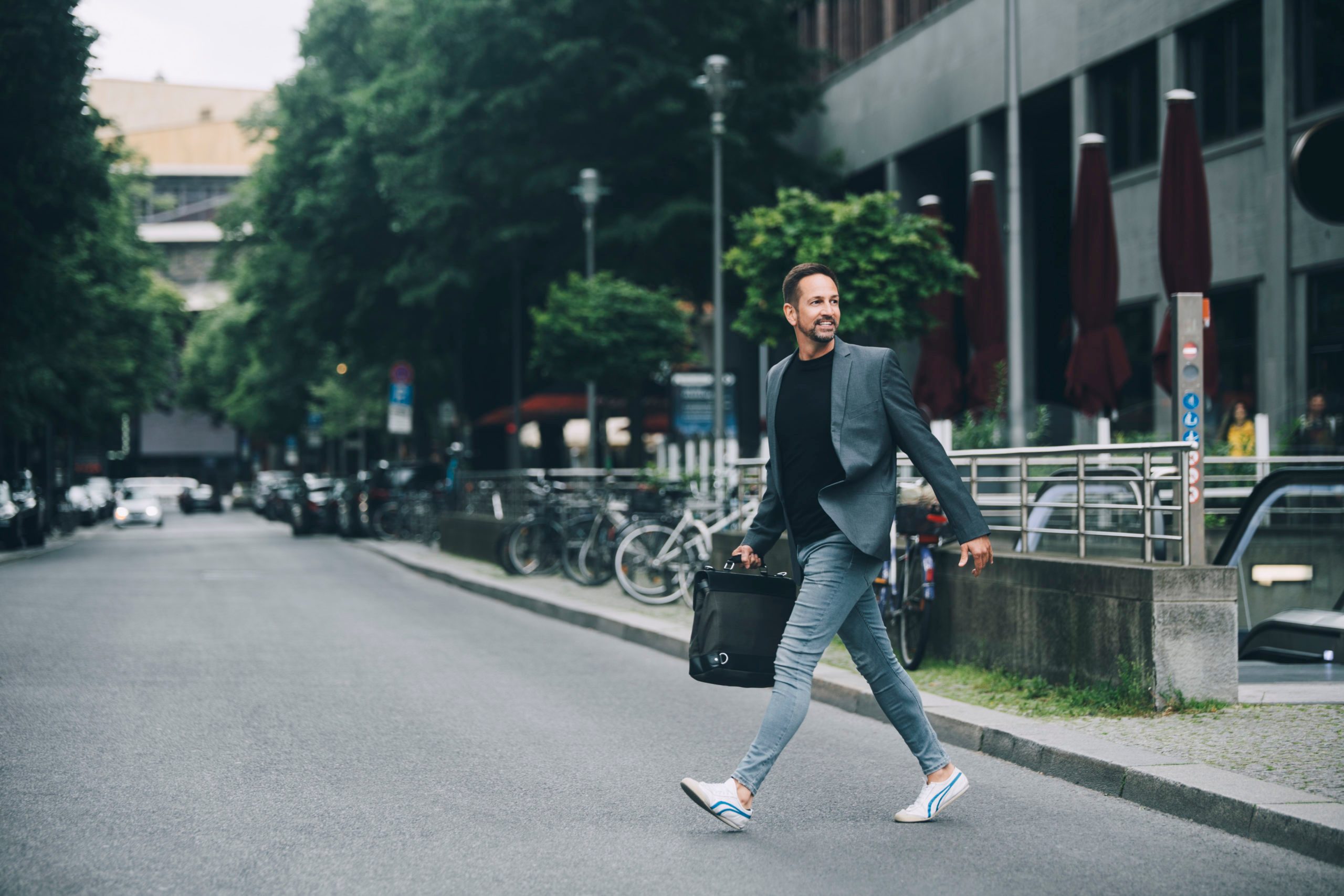 Full length of confident businessman looking away crossing street in city