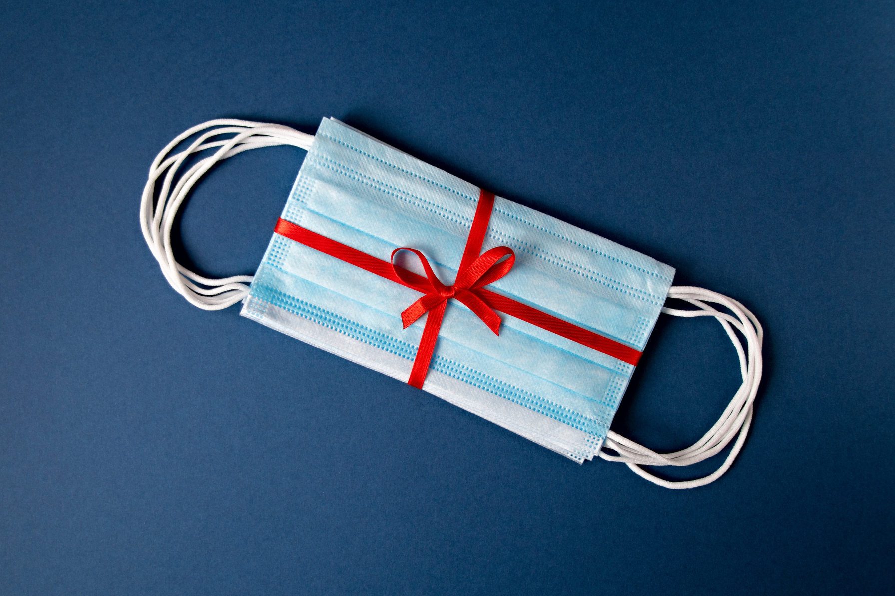 Top view medical protective masks with red ribbon on a blue background with copy space