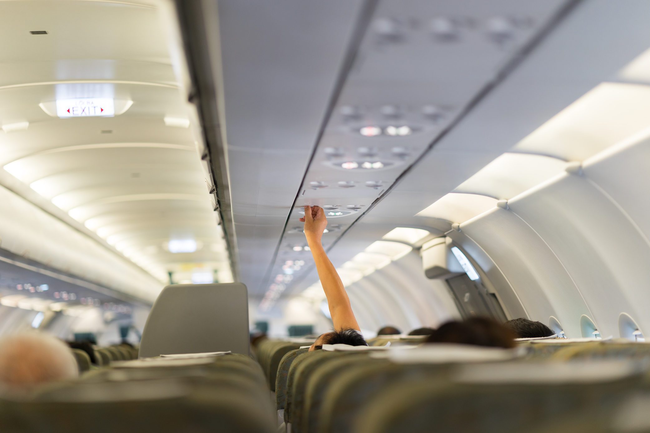 Passenger hand adjusting overheaded electronic inside airplane. Closeup