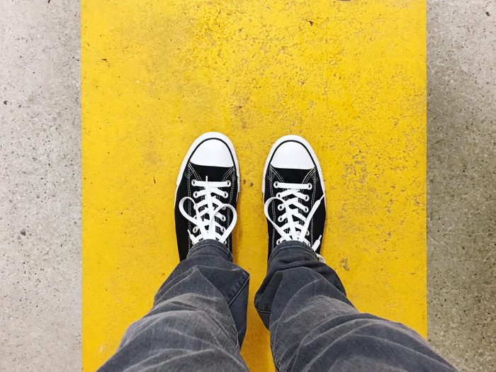 Low Section Of Man Standing On Yellow Concrete Footpath