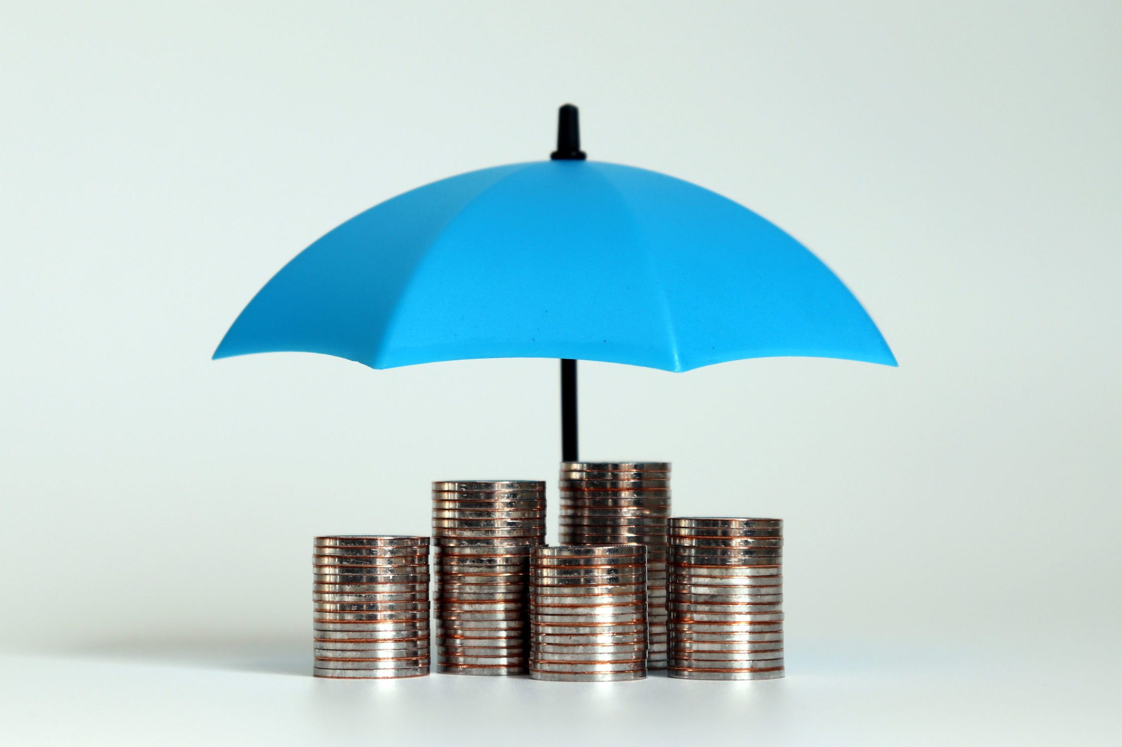 A pile of coins with an open blue umbrella.