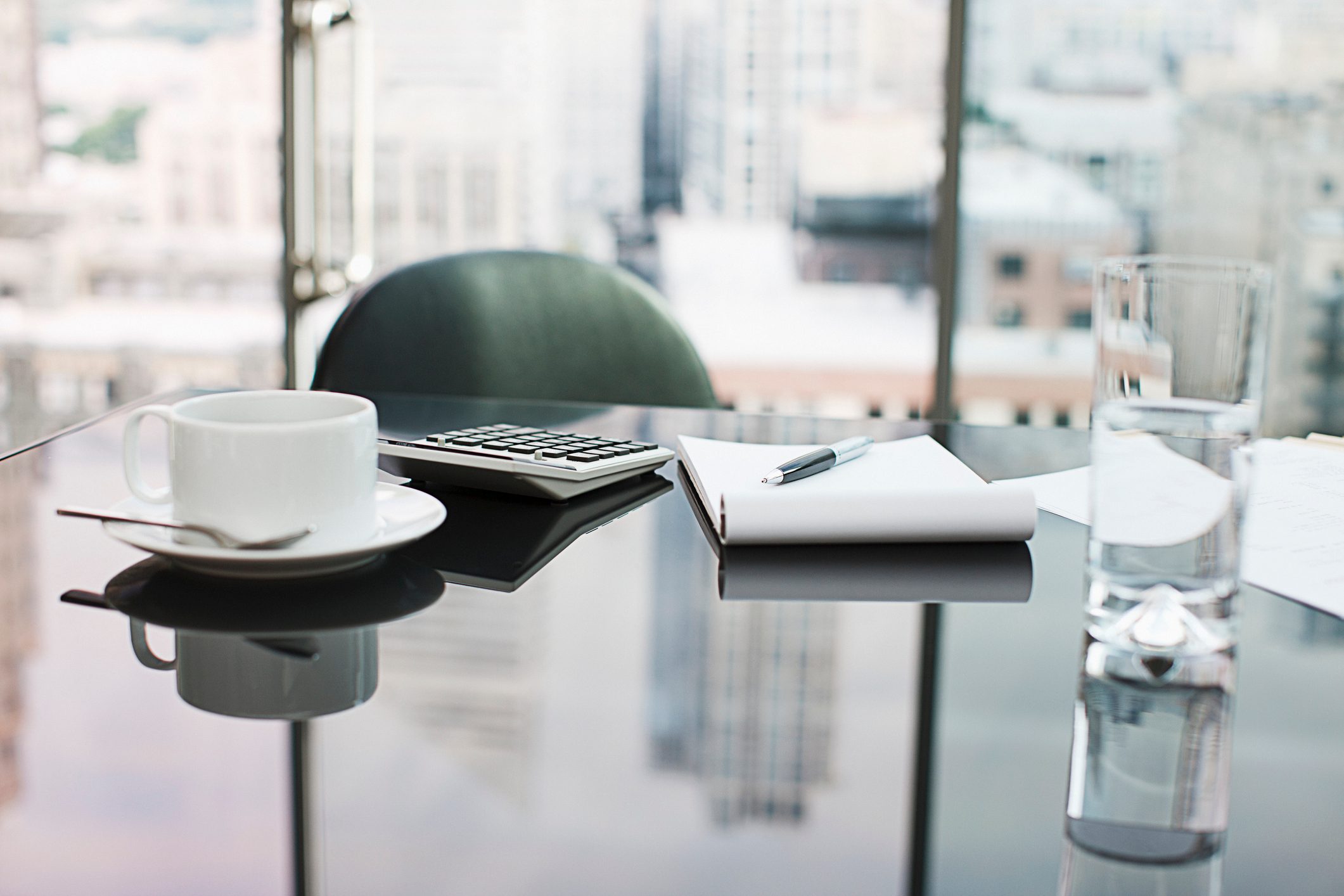 Desk with coffee, calculator, notepad and water