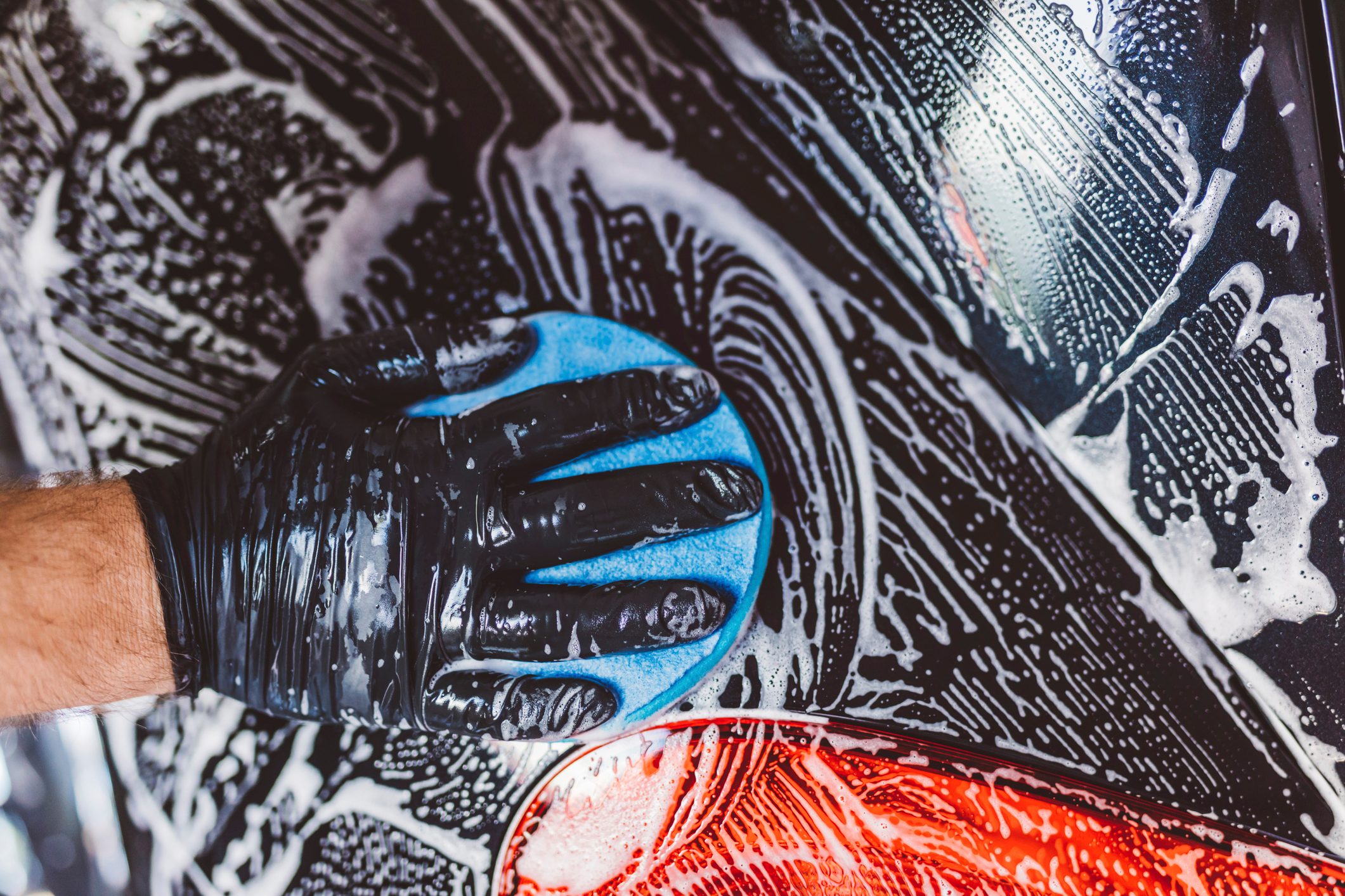 High angle cropped hand of worker cleaning car with soap in workshop