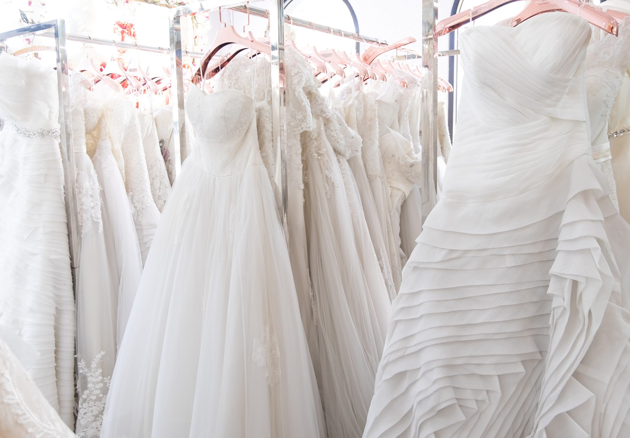 Beautiful, White bridal dress texture on background. Wedding dresses hanging on a hanger interior of bridal salon. Design, fashion modern luxury in detail.