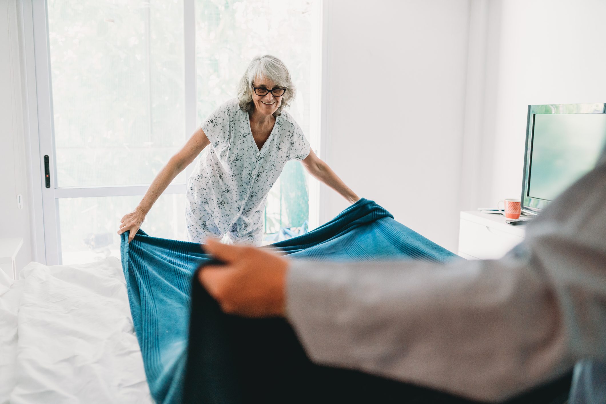 Mature couple making the bed together