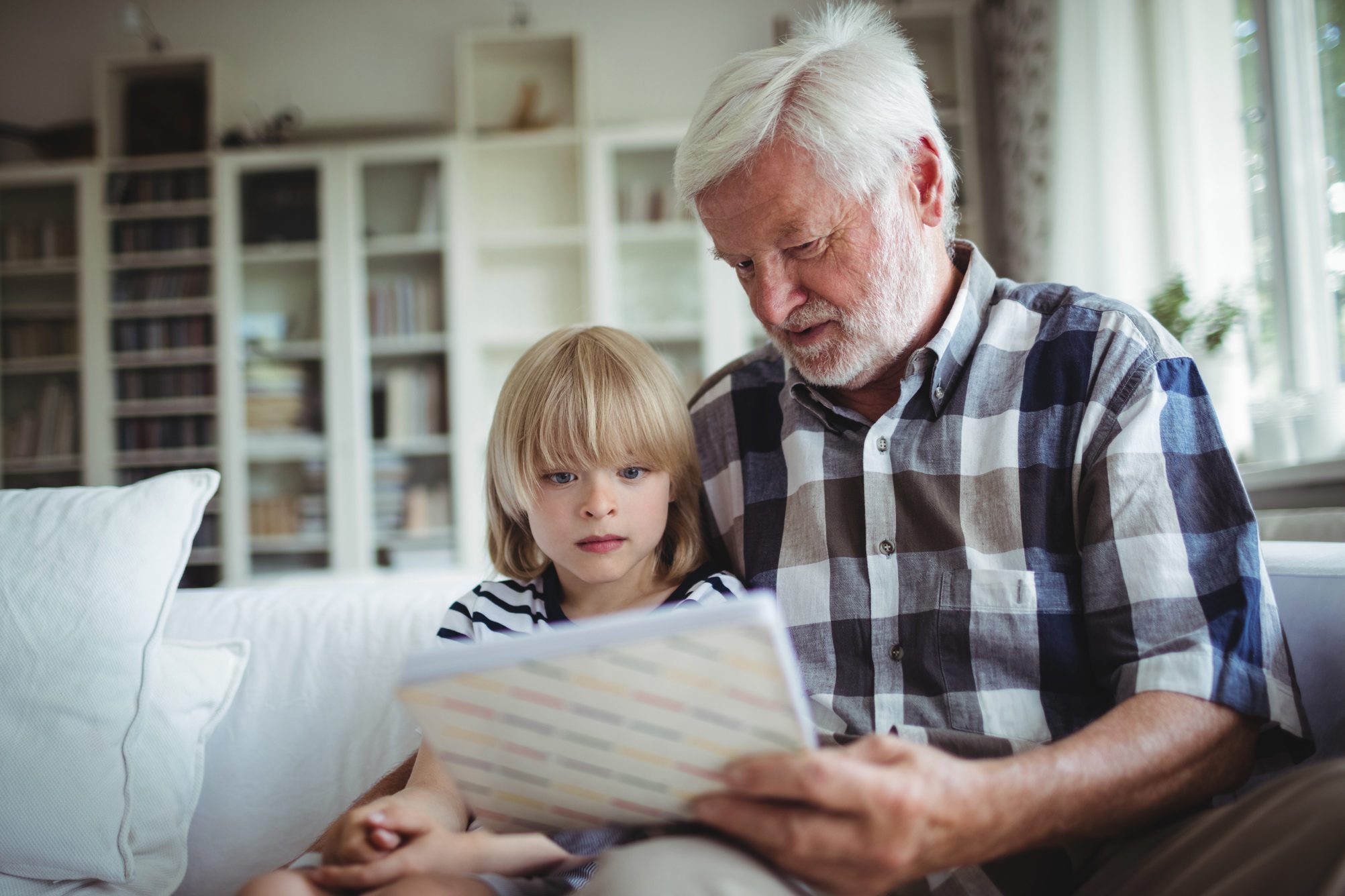 Senior man and her granddaughter looking at a photo album