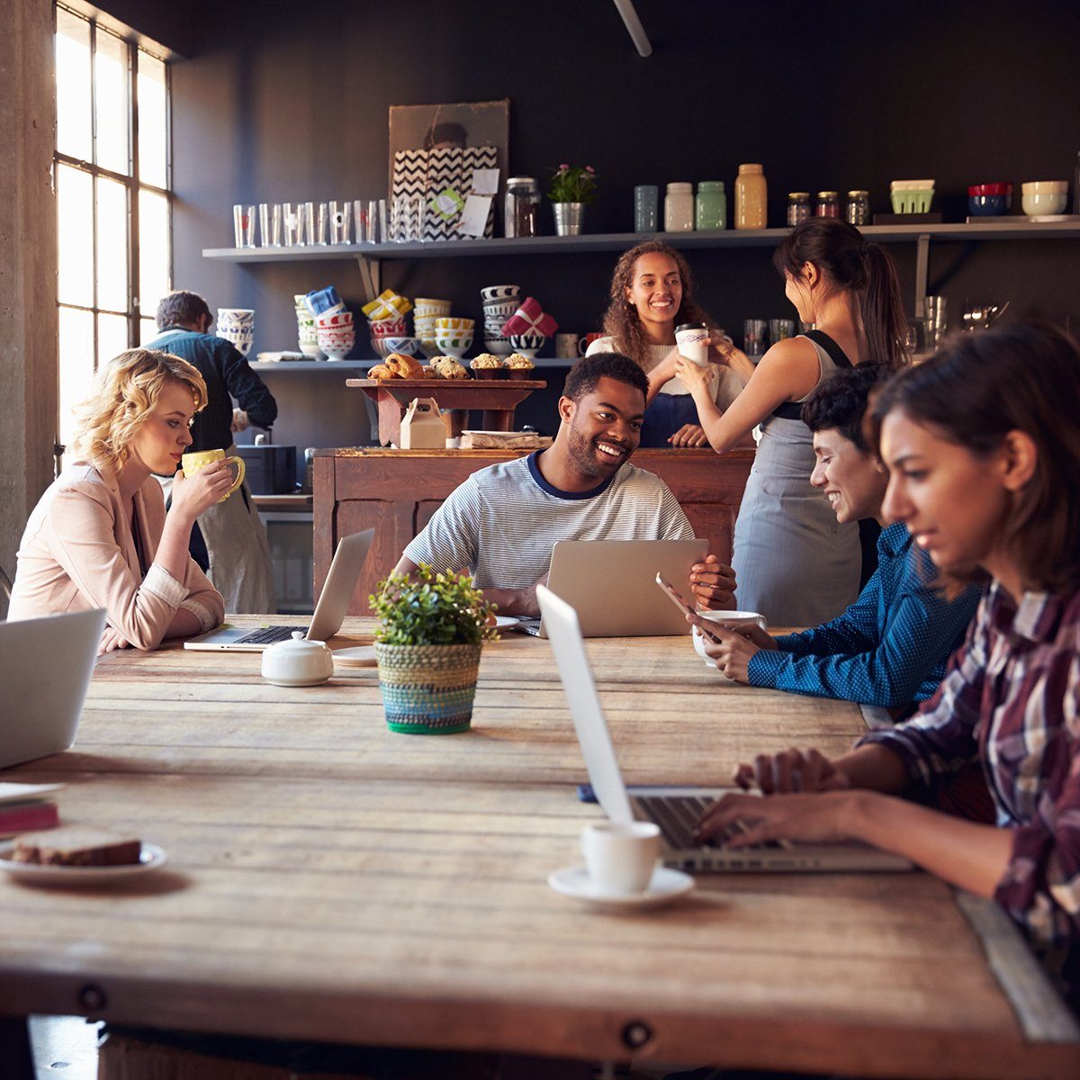 Interior Of Coffee Shop With Customers Using Digital Devices