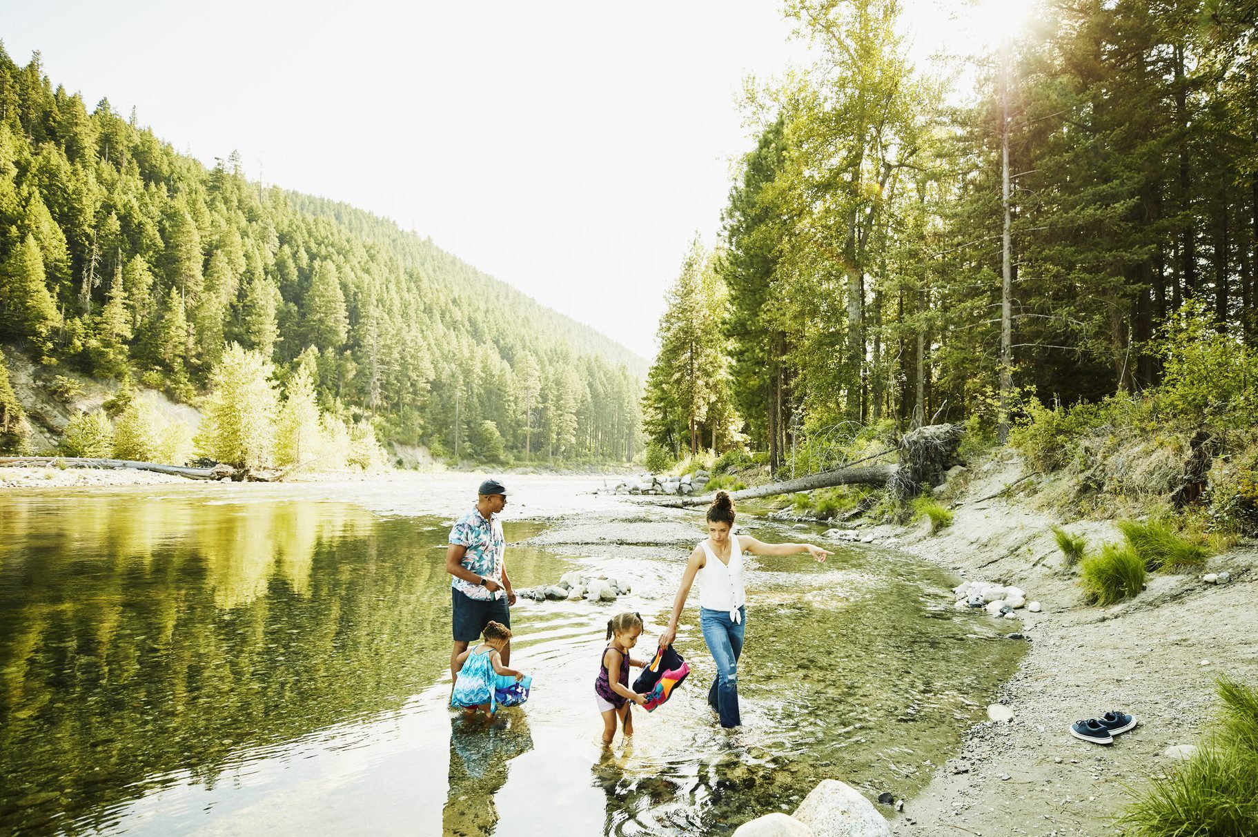 Mother and father playing with daughters in river on summer afternoon