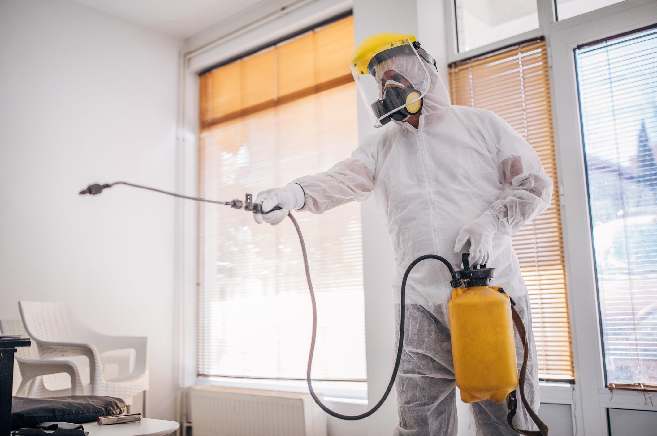 Man in protective suit disinfecting and spraying every room in the building