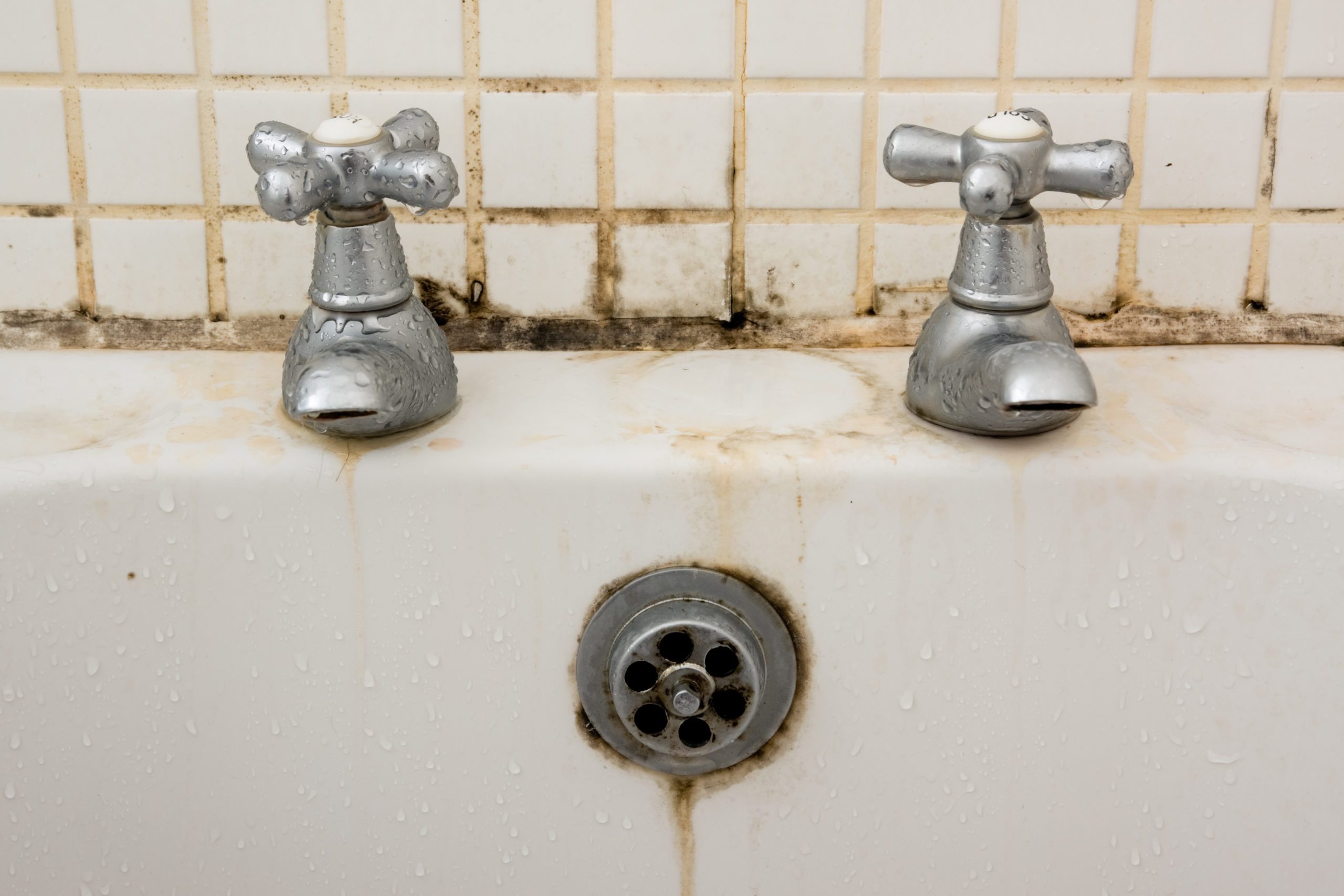 Bathroom dirt and mould on grouting and tiles behind taps