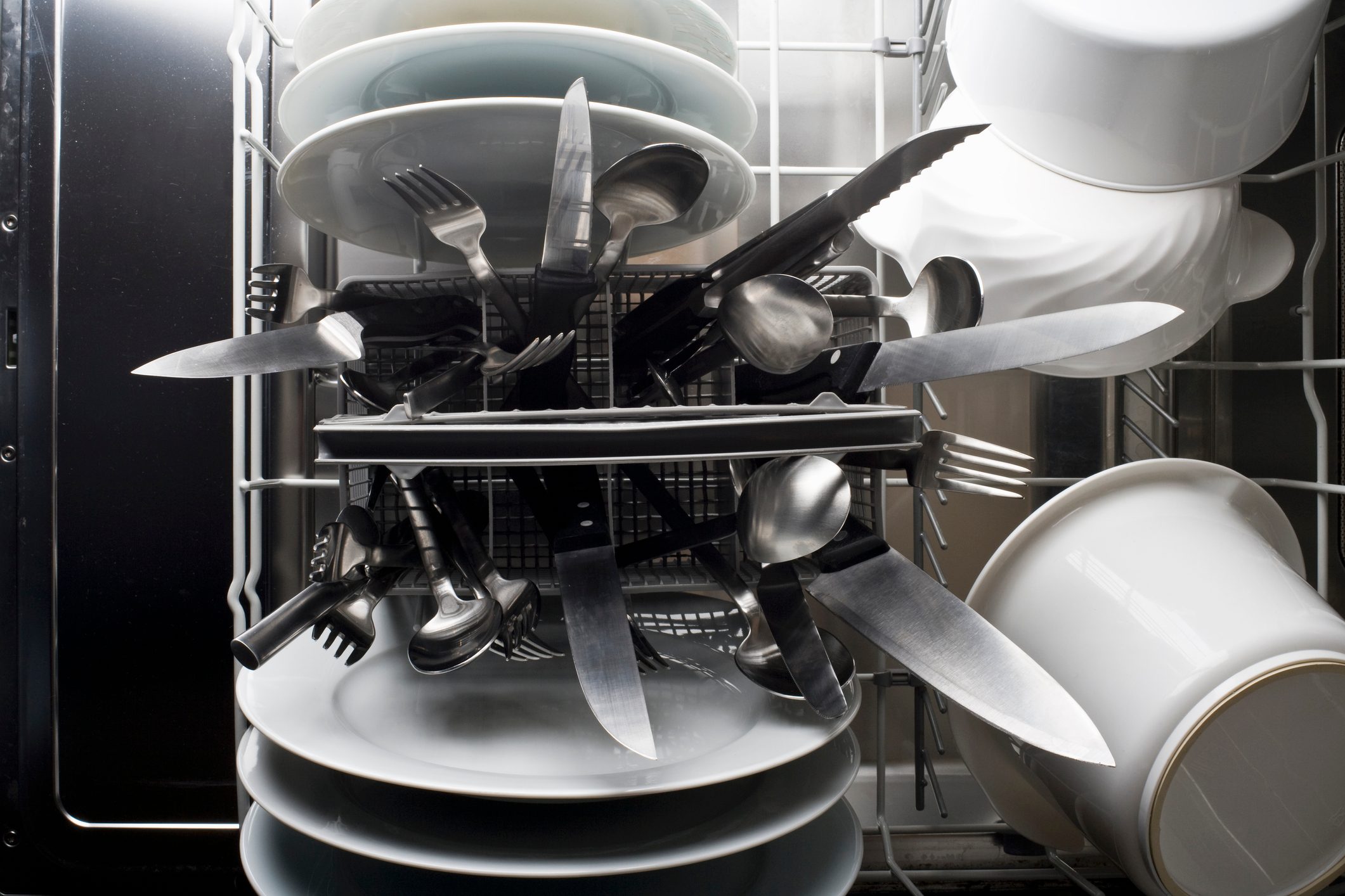 A dishwasher with knives sticking dangerously point side up